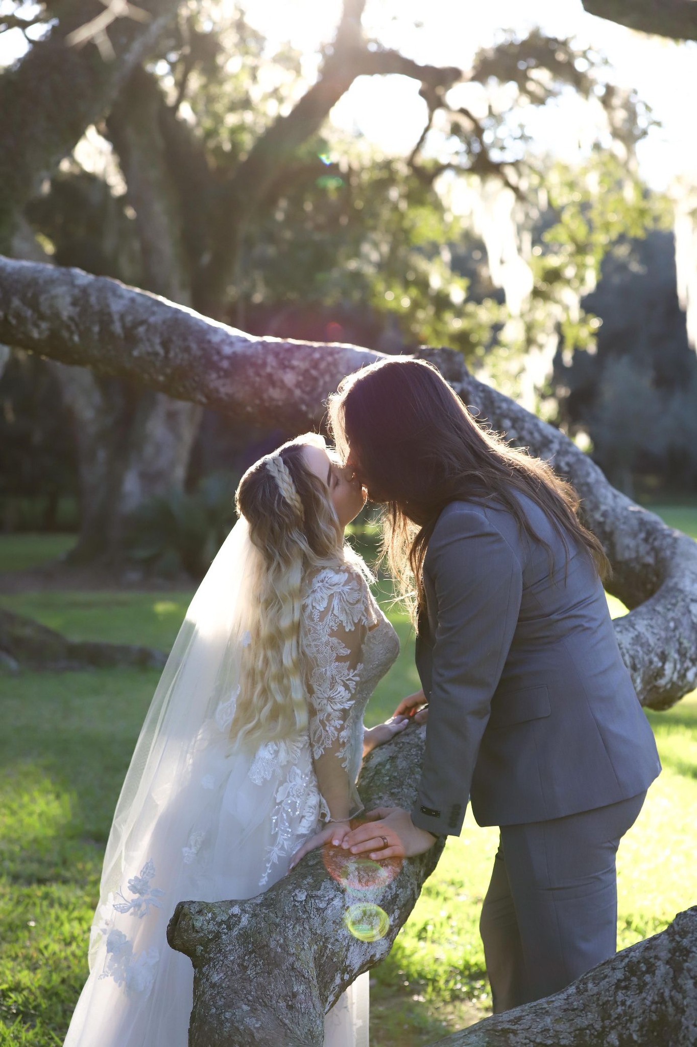 Couple sharing a kiss on a moss-draped oak branch at golden hour — engagement photography in Acadiana by AG Photography